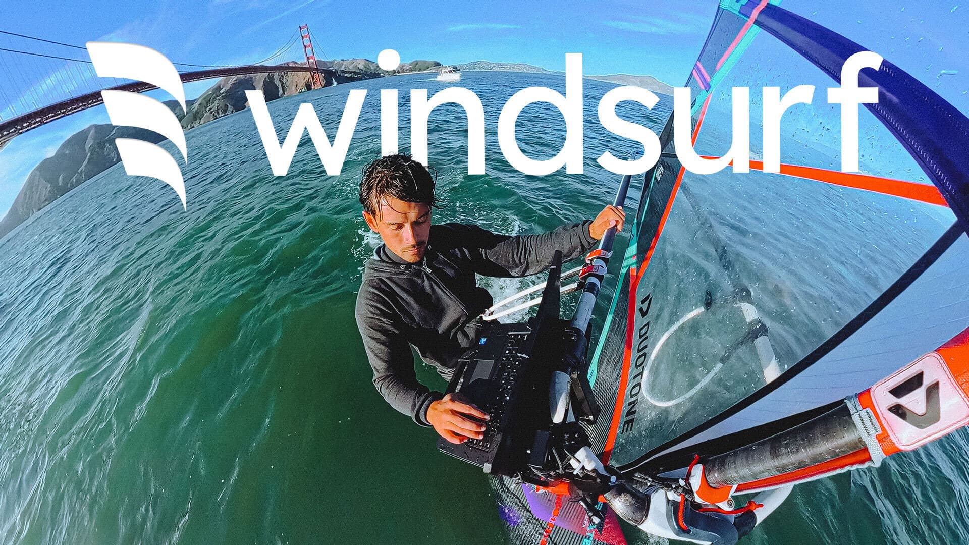 Windsurfer under Golden Gate ridge typing on a computer with Windsurf logo